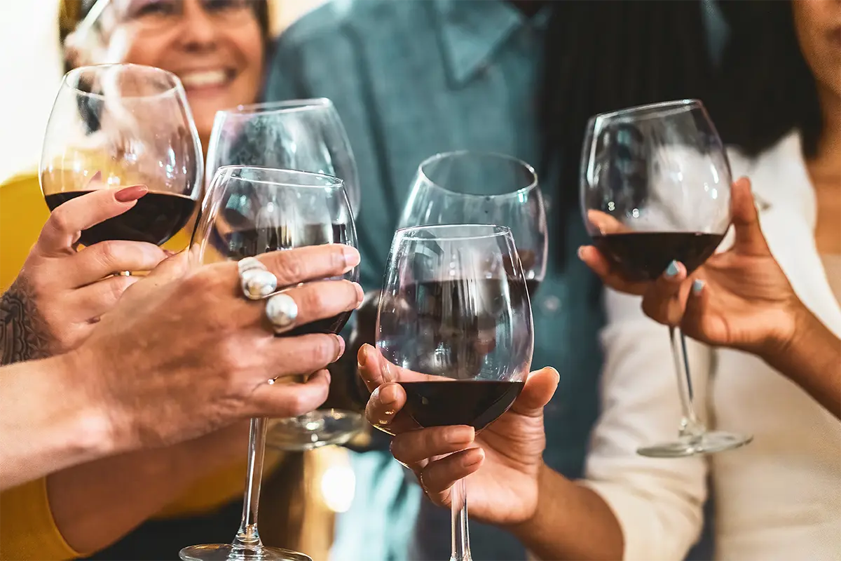 Friends holding wine glasses with wine smiling