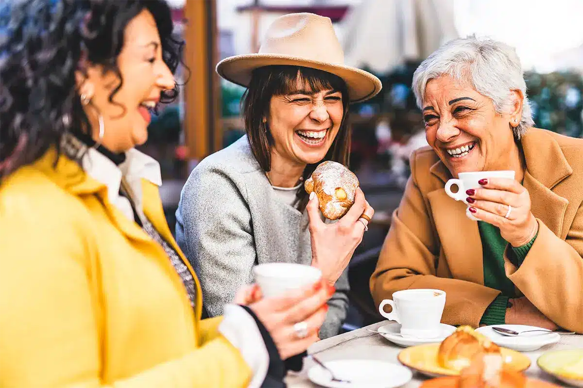 Women friends enjoying coffee and brunch together laughing
